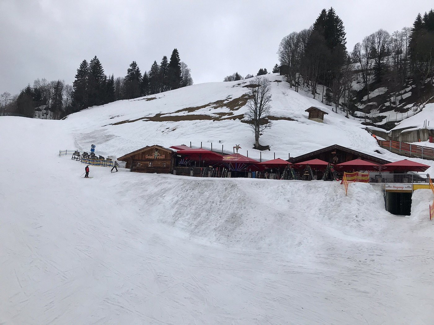 A bustling ski resort in Reitherkogelbahn, Austria, featuring a quaint chalet, busy winter sports scene, and a ski lift against the stunning backdrop of the Tyrolean Alps.