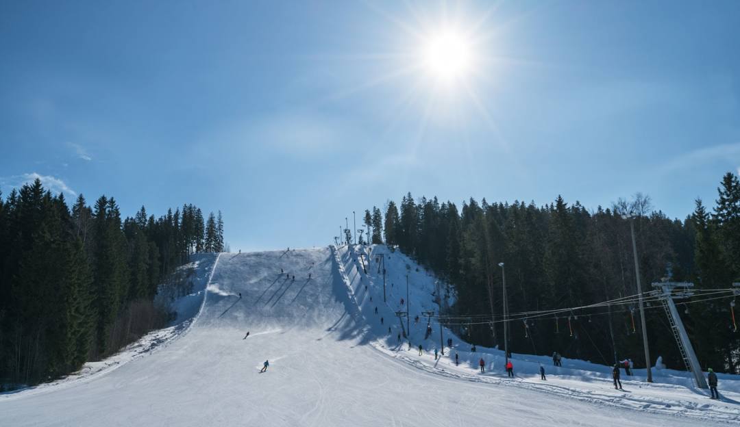 A lively winter sports scene at Himos ski resort in Jämsä West Finland. Skiers are enjoying the snowy slopes with a ski lift prominent in the background. The resort is blanketed in fresh snow inviting for winter fun.