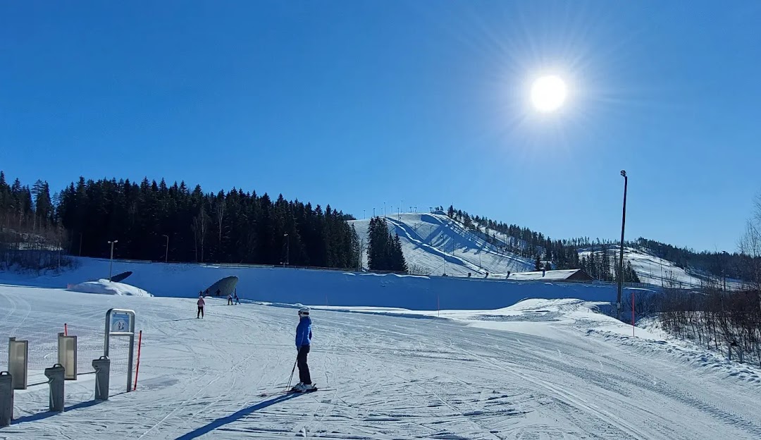 Winter scene at Himos ski resort in Jämsä, West Finland with skiers enjoying the well-groomed slopes. Ski lifts are visible in the background, transporting skiers up the mountain.