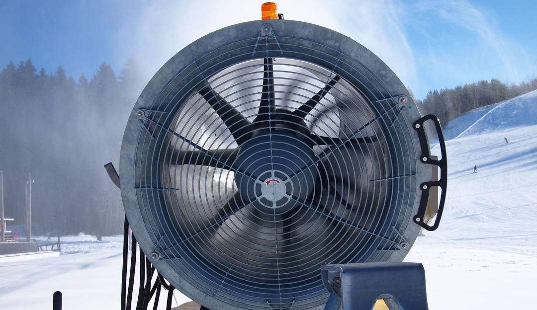 A sunny day at Himos in Jämsä West Finland featuring a charming chalet a ski lift in operation and a lone snowmobile with a skier enjoying the pristine slopes.