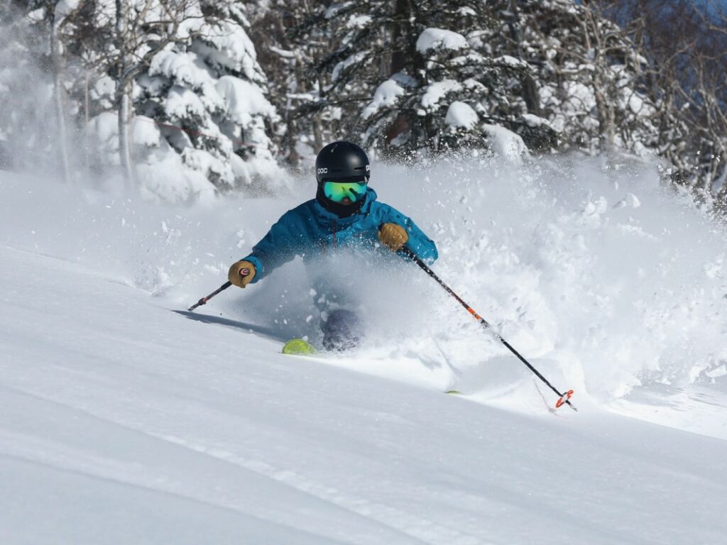 Manza Onsen in Japan - a person in a blue jacket skiing down a hill.