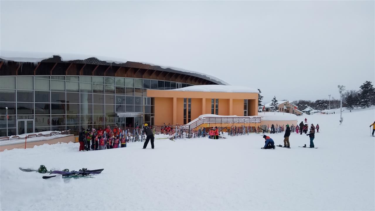 Moya Hills in Japan: a group of people standing in the snow outside of a building.
