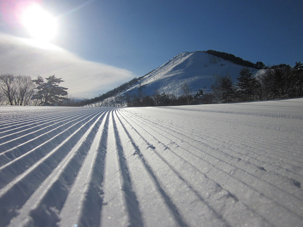 A skier enjoying a winter day at Moya Hills ski resort in Tōhoku, Aomori, Japan, with a charming chalet in view.