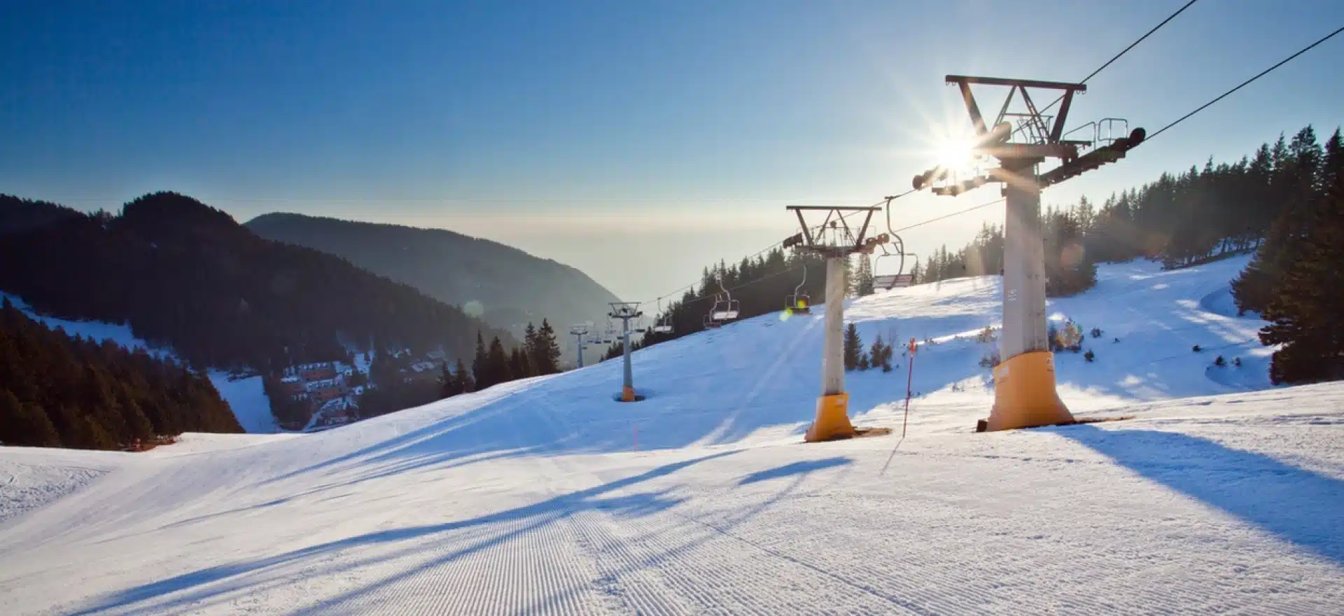 Winter sports scene at Golte Ski Resort, Rečica ob Savinji, Slovenia. A skier heads down pristine white slopes under a ski lift, framed by a stunning winter landscape.