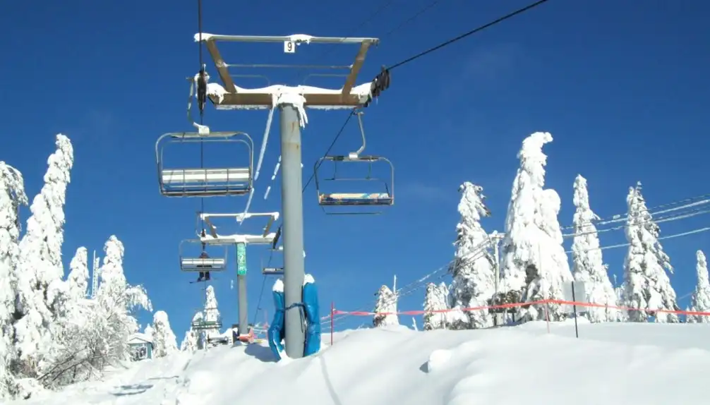 Ski lift operating at the Mont-Kanasuta ski resort in Quebec, Canada. Skiers enjoying winter sports amidst a beautiful snowy landscape.