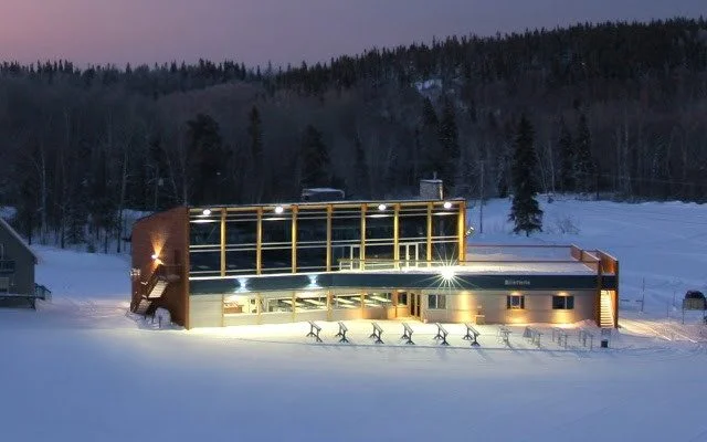 Winter scene at Mont-Kanasuta in Quebec, Canada showcasing a bustling ski resort nestled in wintry forest, with a charming lodge on side, accentuating the essence of a winter sports centre.
