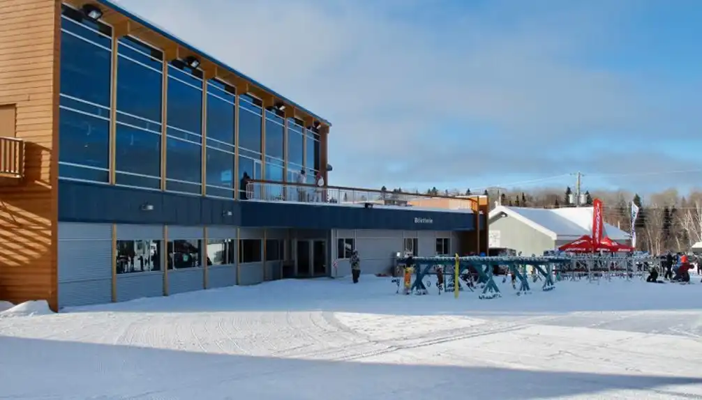 View of Mont-Kanasuta in Quebec, Canada highlighting its winter sports centre, a bustling scene of winter sports enthusiasts. Elements of a ski resort are also visible.