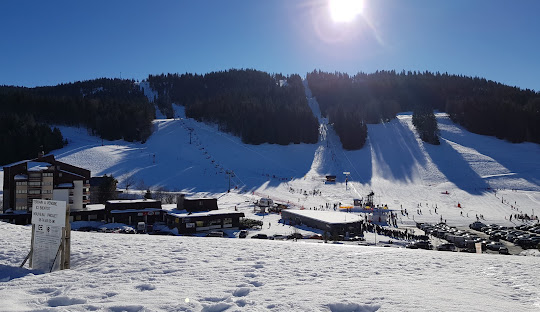 Winter scene at La Serra ski resort in Les Rousses, France, featuring a charming chalet, snow-covered slopes, and various winter sports activities.