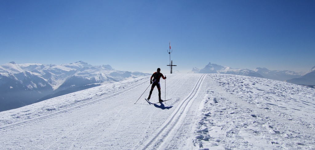 A skier gliding down the snow-covered slopes of Colle di Joux, with charming chalets and a ski lift in the backdrop, offering an idyllic winter sports scene in Aosta, Italy.