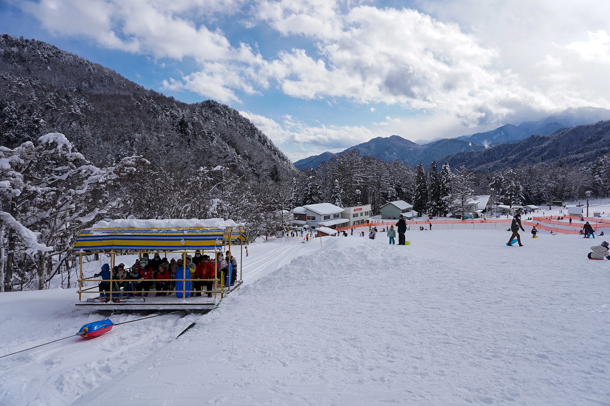 Blue Resort Yanaba in Japan - a group of people riding down a snow covered ski slope.