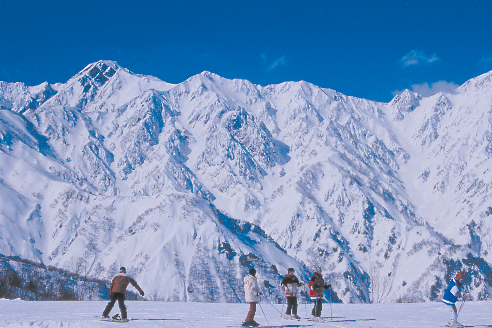 Blue Resort Yanaba in Japan - a group of people skiing down a mountain.
