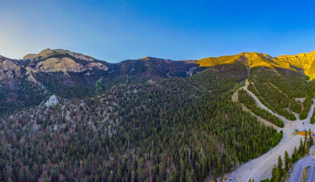 View of a mountain at Las Vegas Ski and Snowboard Resort – Lee Canyon with a chalet nearby. Sparse decorations suggest a winter sports scene.