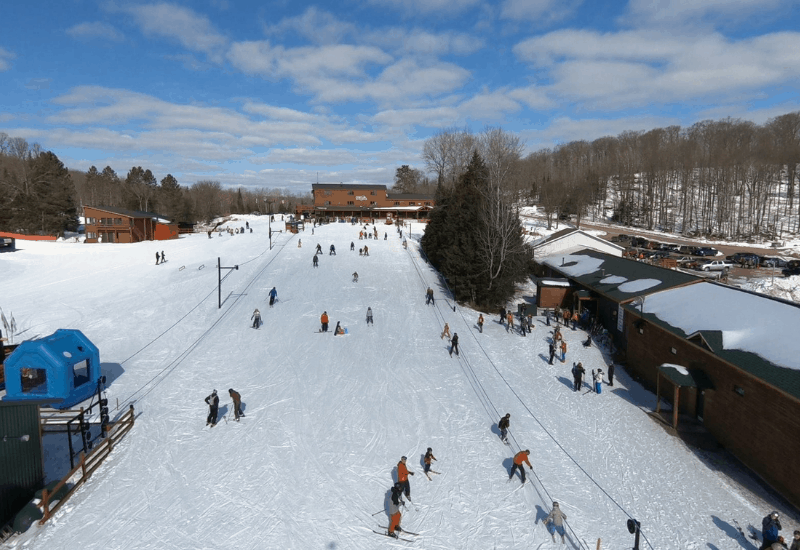 Winter sports enthusiasts enjoying their day at the Ski Brule resort in Iron River, Michigan, highlighting the expansive ski slopes, bustling with activity.
