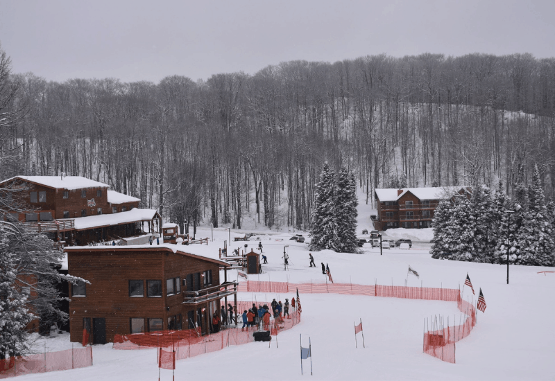 A winter sports scene at Ski Brule in Iron River Michigan showcasing snow-covered slopes a ski lift and the infrastructure of a ski resort surrounded by stunning winter scenery.