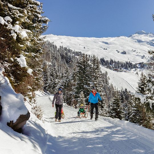 A family and group of people enjoying a winter sports scene at the Hochzeiger-Jerzens ski resort in the Tyrolean Oberland Austria with a cozy chalet in the backdrop.