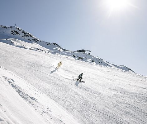 A skier enjoying a sunny day at the Hochzeiger - Jerzens ski resort in Tyrol Austria with charming chalets nestled within the winter sports scene.