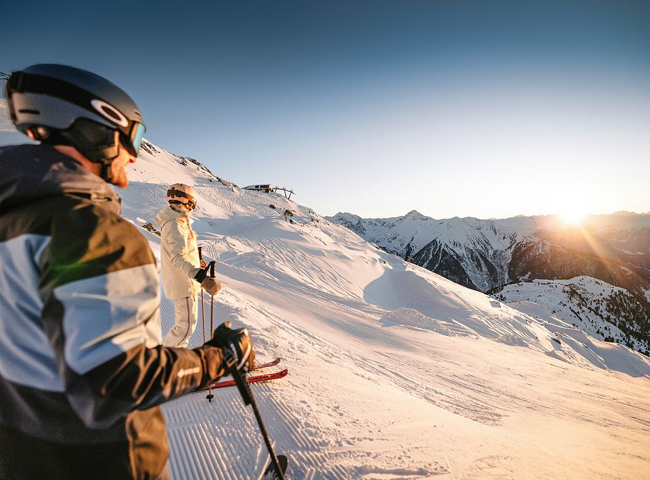A winter sports scene at the Hochzeiger-Jerzens resort in Tiroler Oberland Tyrol Austria featuring a skier and potentially a snowboarder amidst an active day of skiing.