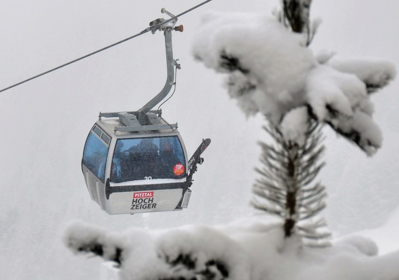 A skier is enjoying a day on the slopes at the Hochzeiger-Jerzens ski resort in Tyrol Austria. A ski lift is in operation nearby and a charming chalet and snowmobile are visible in the background.