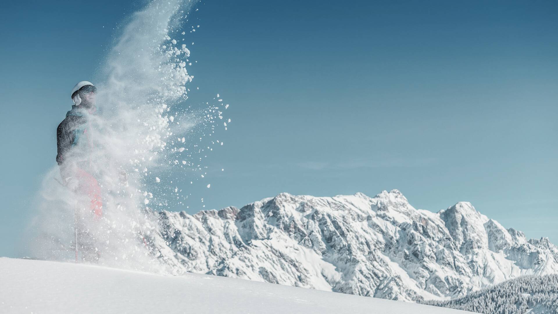 A skier and snowboarder enjoy a winter sports scene at the Hochkonigin ski resort in Hochkönig, Austria, surrounded by the breathtaking beauty of snow-filled mountains.