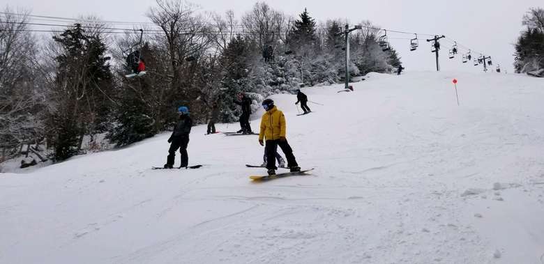McCauley Mountain Ski Center in USA - a group of people riding down a snow covered slope.