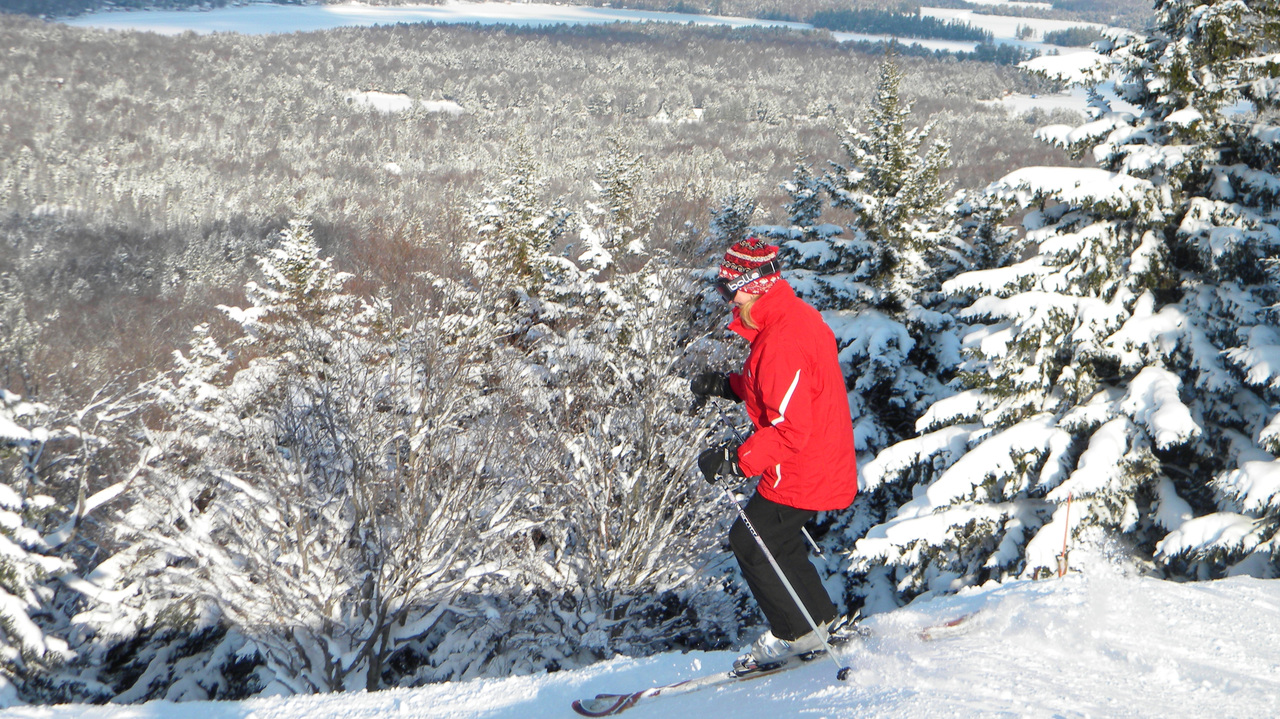 McCauley Mountain Ski Center in USA - a person in a red jacket on a snowboard.