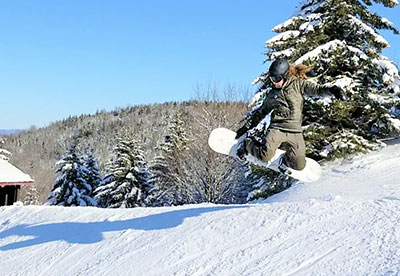 McCauley Mountain Ski Center in USA - a person jumping in the air on a snowboard.