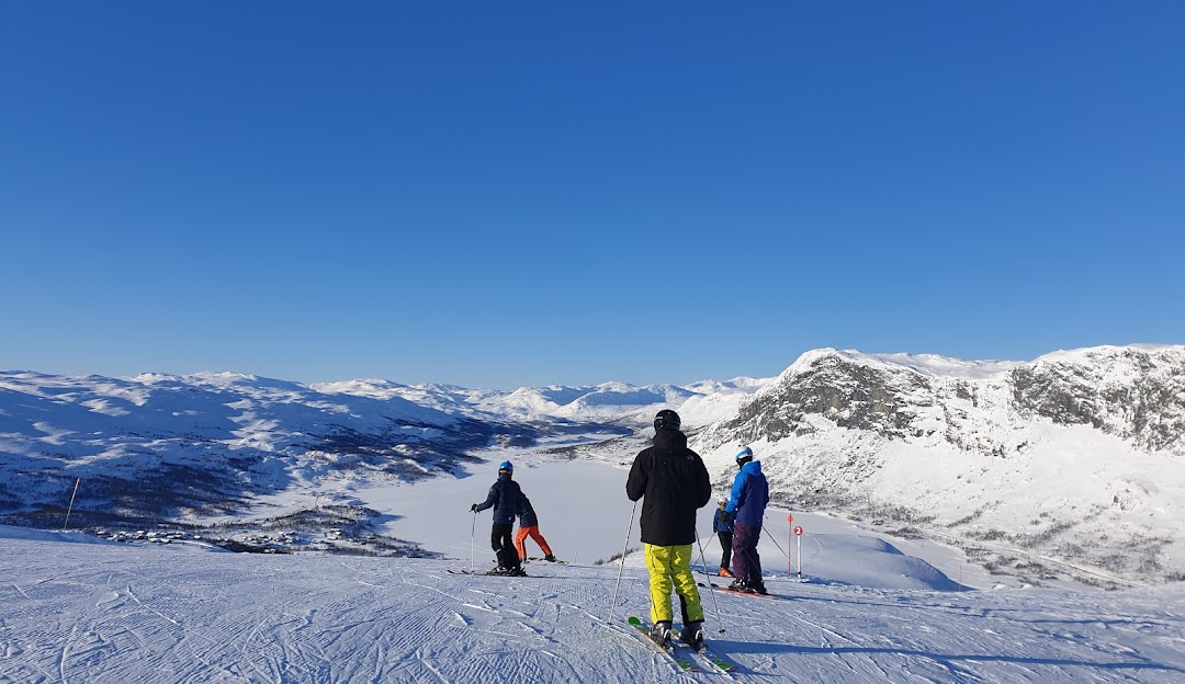 Family enjoying skiing at Tyin-Filefjell ski resort in Valdres Tyinkrysset Oppland Norway with a charming challet in the scenic snowy landscape.