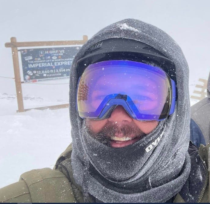 A skier and a snowboarder enjoying their winter sports at the Ski-Waldheimat Hauereck resort in Austria, with a charming chalet in the backdrop.
