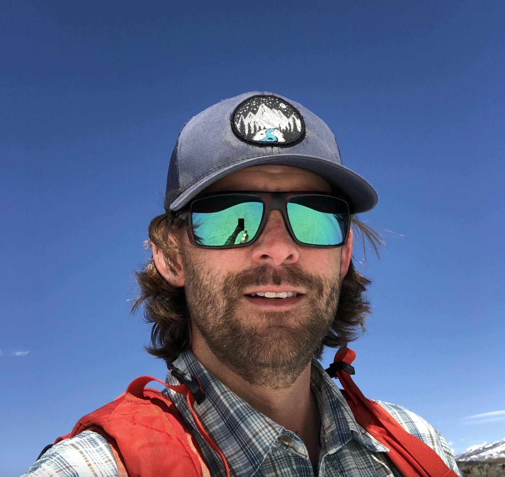 A skier glides down the sunlit slopes of Ski-Waldheimat Hauereck in St. Kathrein/Hauenstein, Austria, with a snowboarder in the distance and mountains framing the scene.