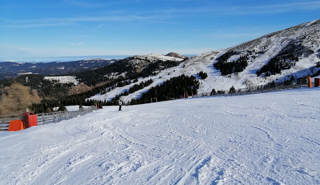 Winter scene at Koralpe in Lower Carinthia, Wolfsberg, Austria, featuring a cozy chalet and skiers enjoying the ski resort amid pristine snowy landscapes.