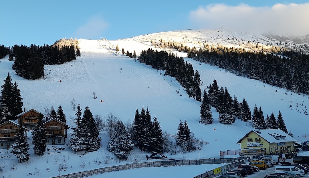 Ski resort at Koralpe in Lower Carinthia, Austria, featuring snow-covered slopes, a charming chalet and breathtaking winter scenery. People engaged in winter sports are visible.