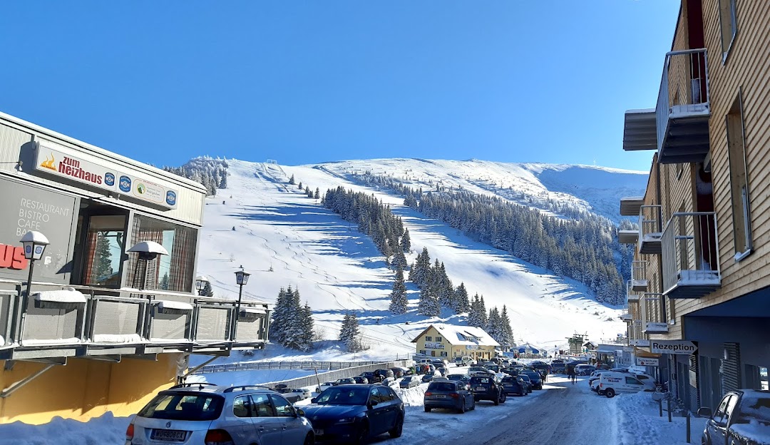 Austrian ski resort in Koralpe, Wolfsberg, showcasing stunning winter scenery. A chalet can be seen amidst the winter sports scene, indicative of an active sports centre.