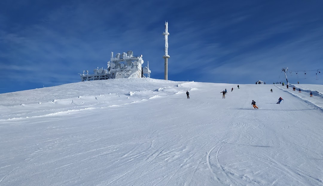 A skier at the Koralpe ski resort in Wolfsberg Austria amidst a lively winter sports scene. The image also features a ski lift at the winter sports centre.