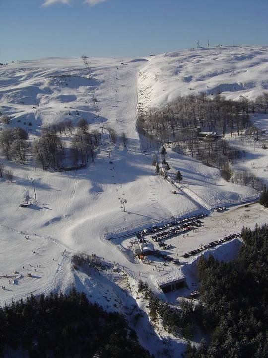 View of Risalita sciistica Carpegna - Eremo ski resort in Italy featuring a traditional chalet ski lift & bustling winter sports scene.