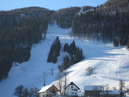A picturesque view of the Javornik ski resort in Črni vrh nad Idrijo Slovenia featuring ski lifts and a charming chalet amidst a scenic winter landscape.
