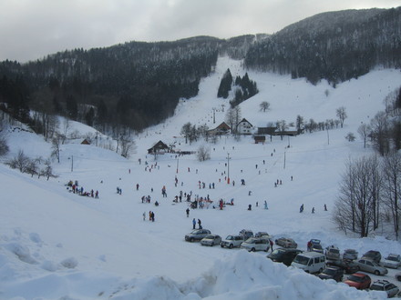 A picturesque view of the Javornik ski resort in Slovenia showcasing a lively winter sports scene. Features include a chalet and a ski lift in the distance.