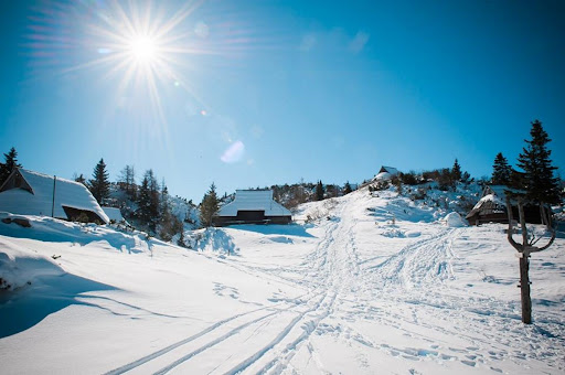 Velika Planina in Slovenia - the sun is shining over a snow covered road.