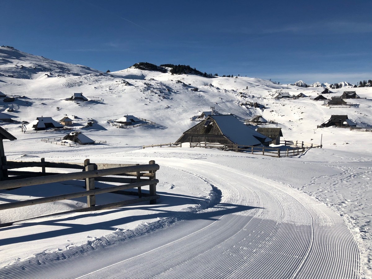 Velika Planina in Slovenia - a snow covered ski slope with snow covered houses in the background.