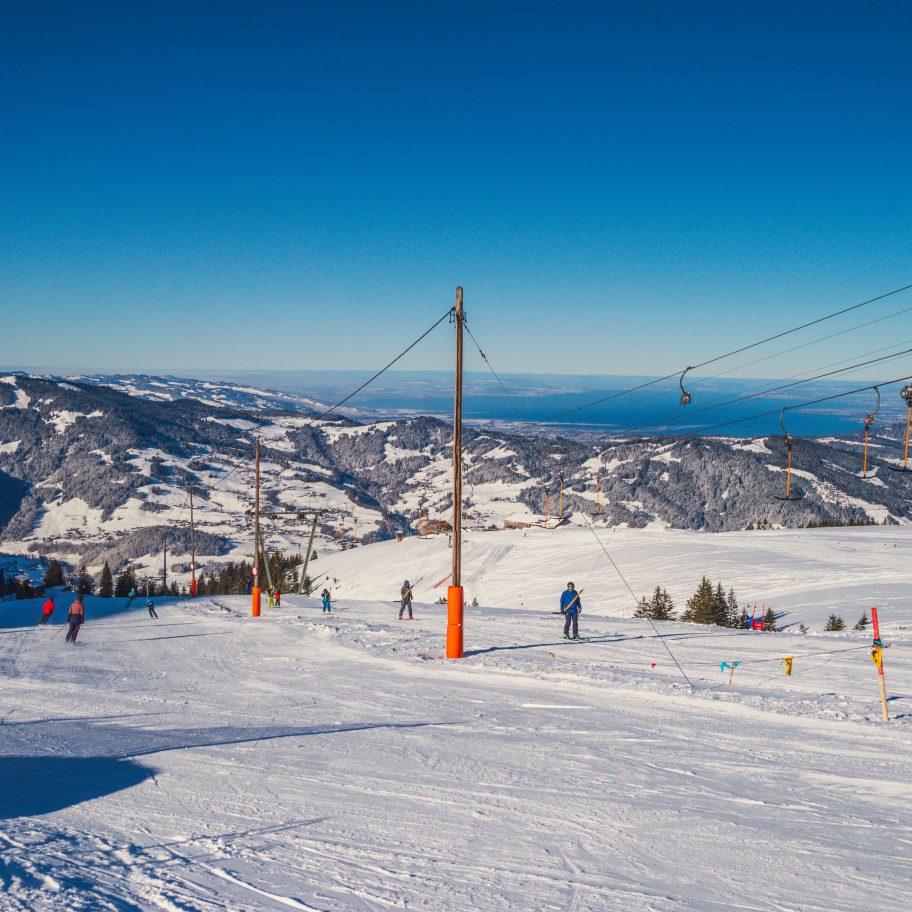 Niedere – Andelsbuch | Bezau in Austria - a ski slope with people skiing down it.