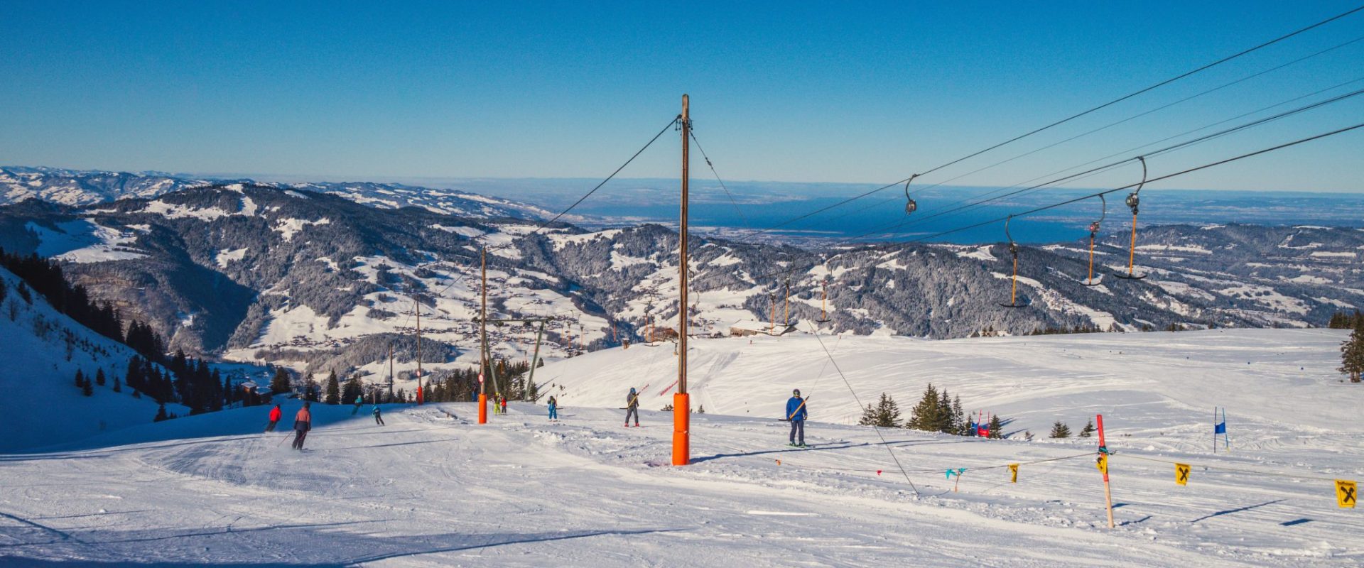 Niedere – Andelsbuch | Bezau in Austria - a ski slope with people skiing down it.