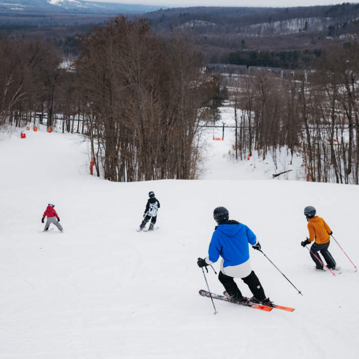 Winter sports scene at Horseshoe Resort in Barrie, Ontario, Canada, bustling with activities of groups of people and families enjoying a day of skiing.