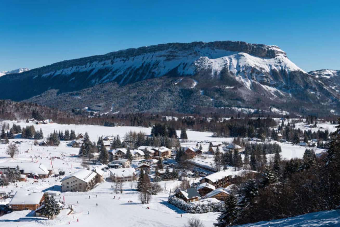 Savoie Grand Revard in France - a snowy town with mountains in the background.
