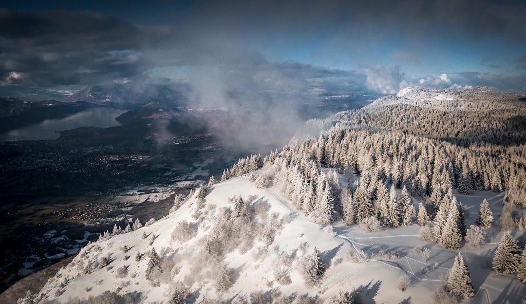 Winter sports scene at Savoie Grand Revard in France featuring a majestic mountain landscaped with a bustling ski resort surrounded by stunning winter scenery.