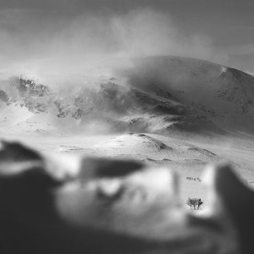 View of the majestic Hallingskarvet mountain in Hovet, Norway. A skier glides through a well-groomed ski resort amidst a stunning winter sports scene, accentuated by the snowy peak.