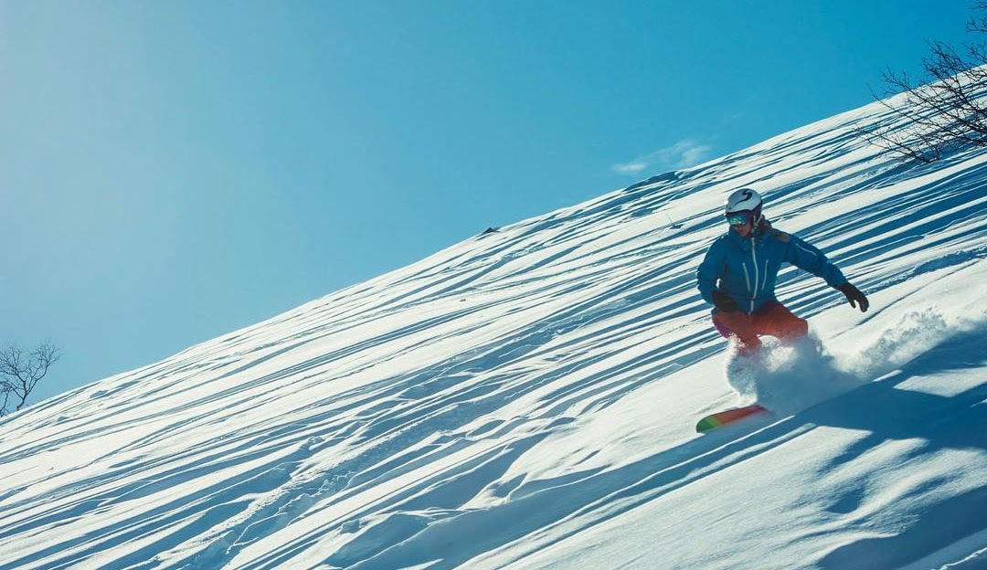 A skier enjoying a winter sports scene at Hallingskarvet in Hovet, Norway. A charming chalet is visible in the snowy landscape, embodying the essence of a ski resort.