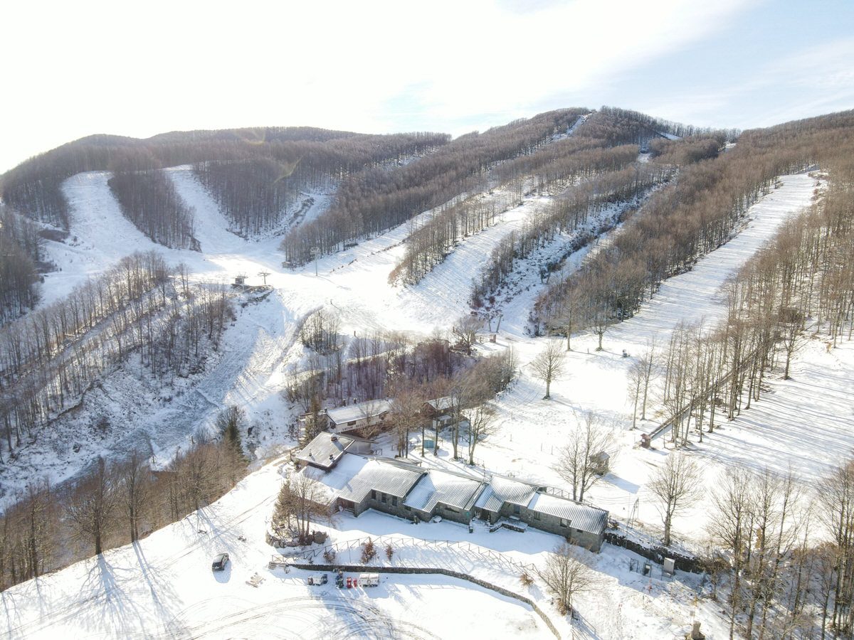 Stunning winter view at the Passo dei Due Santi in Zum Zeri, Italy, highlighting the busy ski resort with skiers dotting the slopes and a ski lift in the distance.