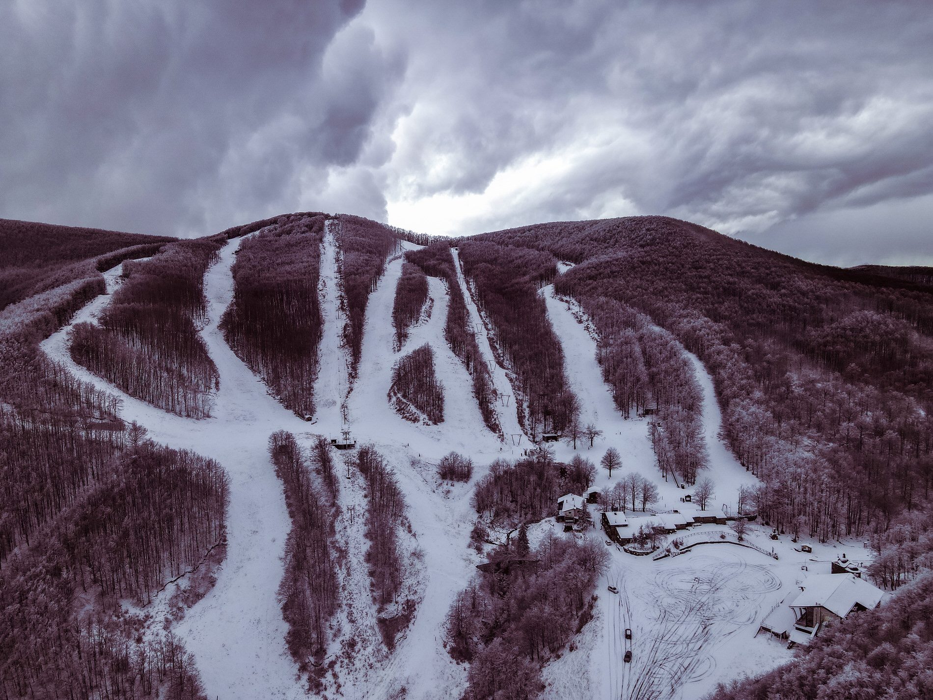 View of the charming Passo dei Due Santi ski resort in Italy; snow-covered slopes welcome skiers, with a distant mountain backdrop. A ski lift can be spotted ready to transport enthusiasts to the peak.