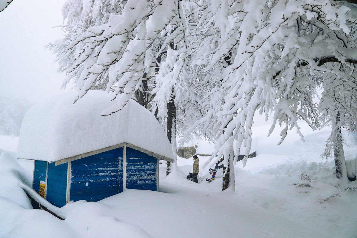 Winter scene at Passo dei Due Santi in Zum Zeri, Italy showing a winter sports centre, mountain hut, and beautiful snowy landscape.