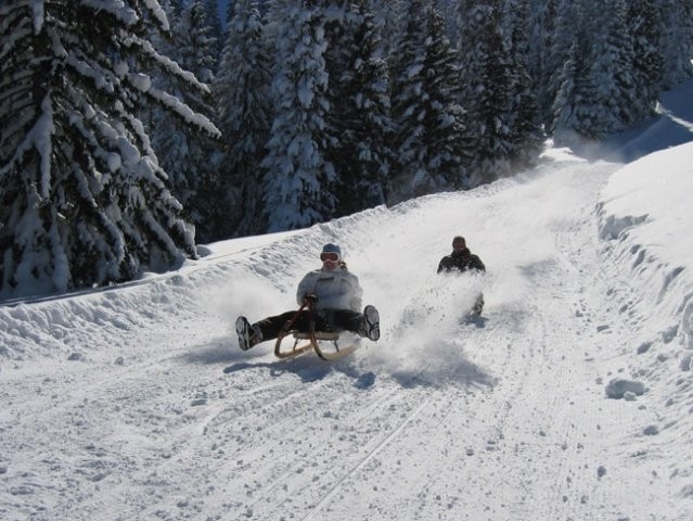 A snowmobile sits amidst a snowy scene in Mörlialp Obwalden in Central Switzerland. Nearby a skier partakes in winter sports at a ski resort with the faint silhouette of a ski lift in the background.