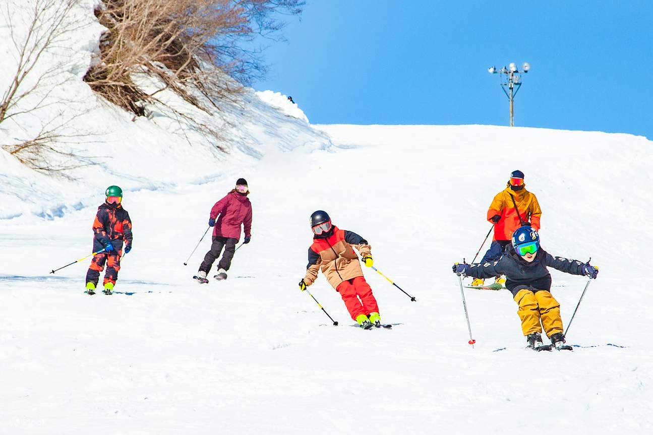Yuzawa Nakazato in Japan - a group of people skiing down a snowy hill.